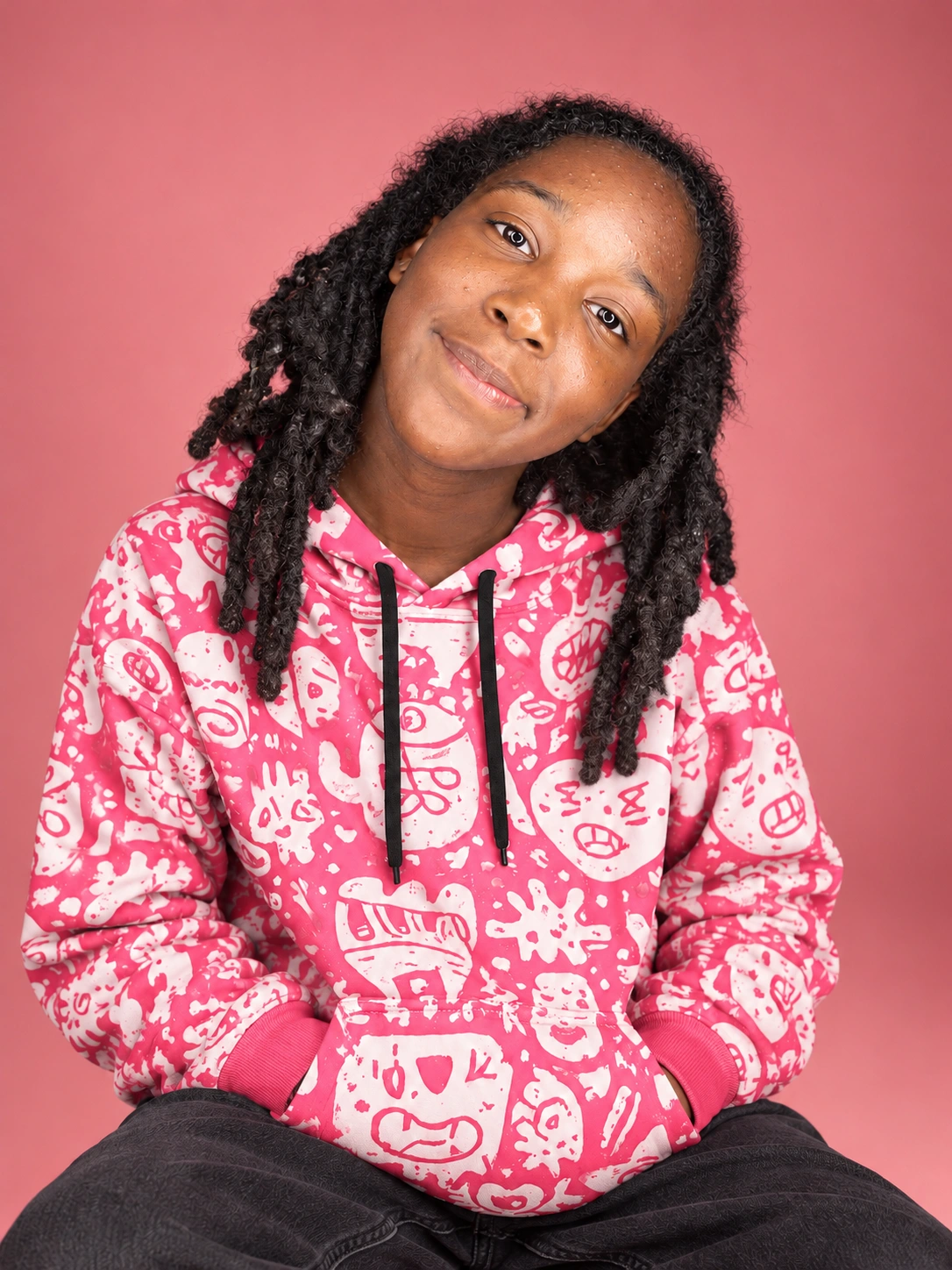 Young brand model wearing the Soft Chaos hoodie in a pink studio